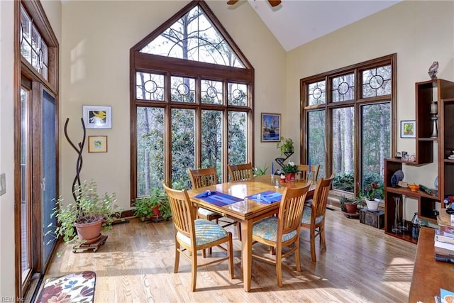 dining area featuring high vaulted ceiling, light wood-style floors, and a ceiling fan