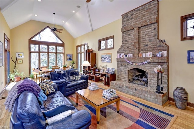 living area with high vaulted ceiling, a ceiling fan, wood finished floors, a fireplace, and baseboards