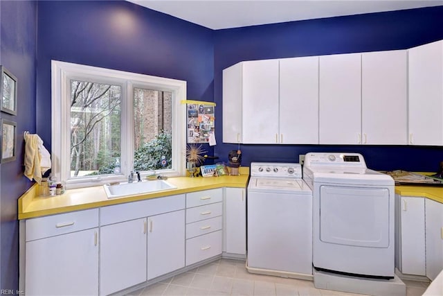 clothes washing area featuring a sink, cabinet space, and washing machine and clothes dryer