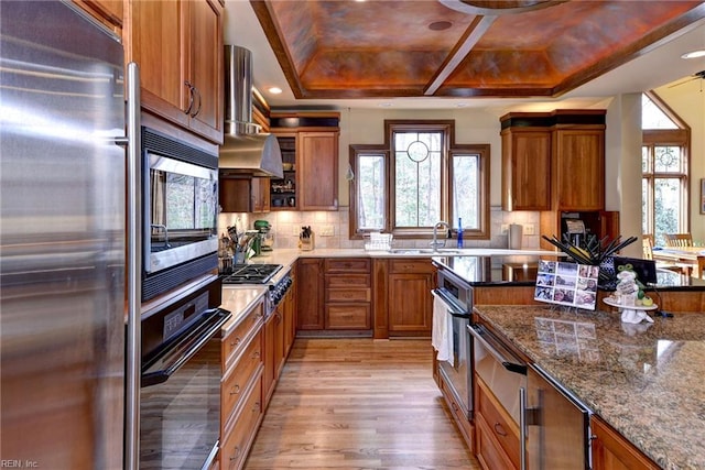 kitchen with exhaust hood, brown cabinets, and stainless steel appliances