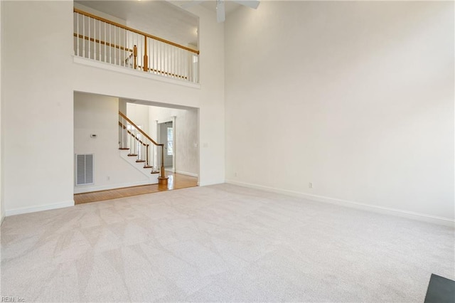 unfurnished living room with carpet floors, baseboards, stairs, and visible vents