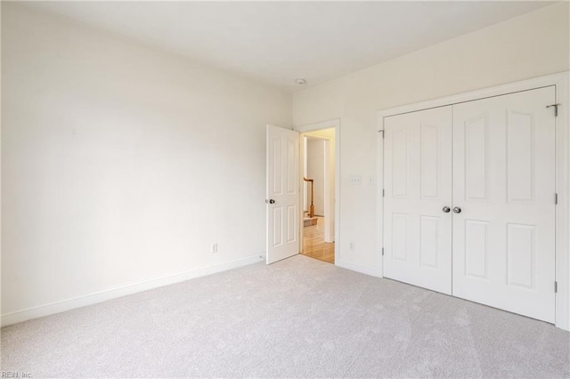 unfurnished bedroom featuring carpet, baseboards, and a closet