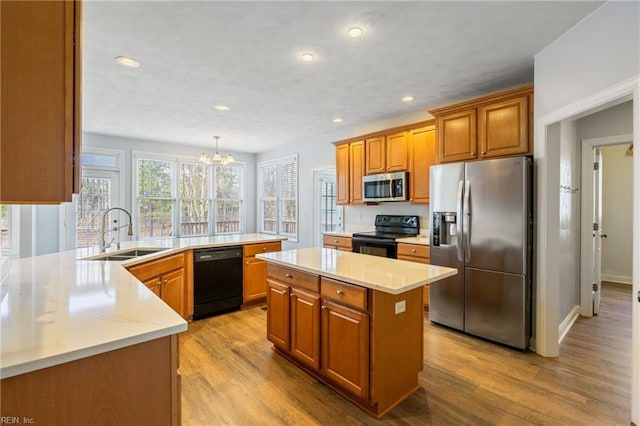 kitchen with recessed lighting, light wood-style flooring, brown cabinetry, a sink, and black appliances