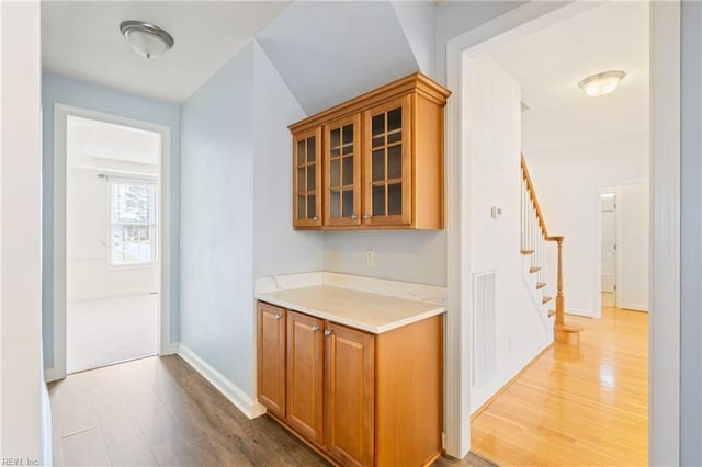 bar with stairs, visible vents, baseboards, and wood finished floors