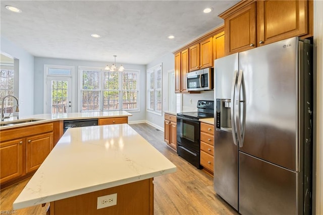 kitchen with stainless steel appliances, light wood-type flooring, a sink, and brown cabinets