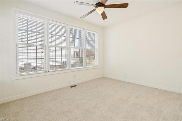 spare room with visible vents, carpet flooring, a ceiling fan, and baseboards