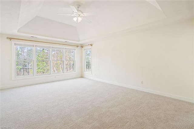 carpeted empty room featuring lofted ceiling, a raised ceiling, a ceiling fan, and baseboards