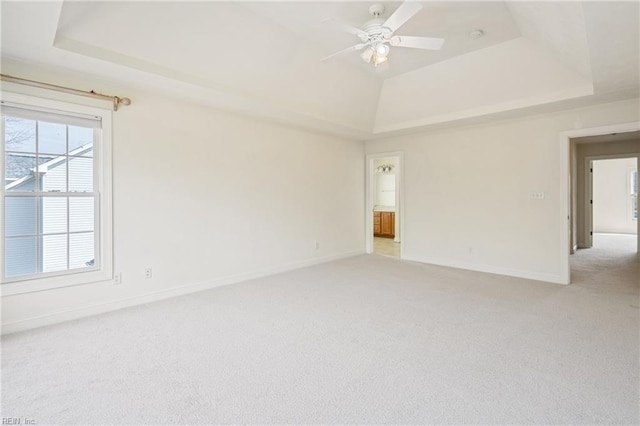 unfurnished room with baseboards, a raised ceiling, and light colored carpet