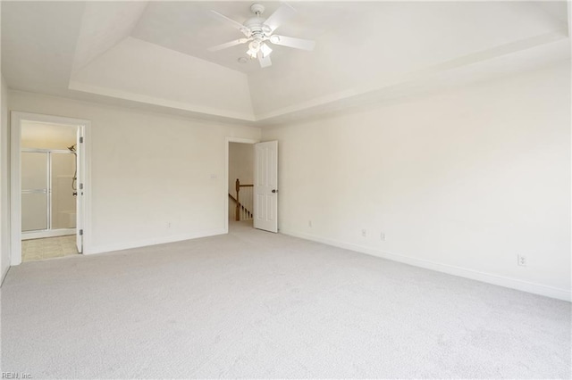 unfurnished room with a ceiling fan, a raised ceiling, light carpet, and baseboards