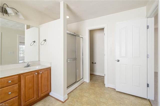 bathroom featuring a stall shower, vanity, and baseboards