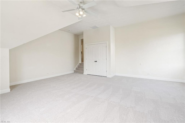 additional living space with light carpet, baseboards, lofted ceiling, ceiling fan, and stairs