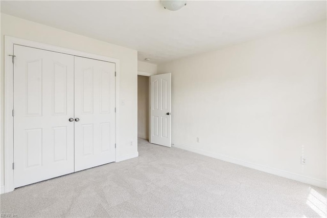 unfurnished bedroom with carpet floors, a closet, and baseboards