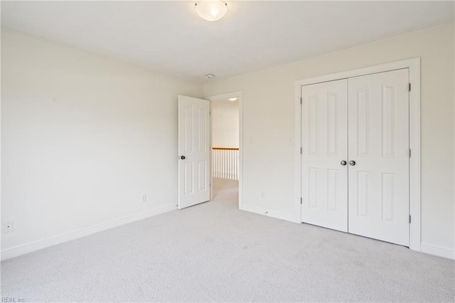 unfurnished bedroom featuring baseboards, a closet, and light colored carpet