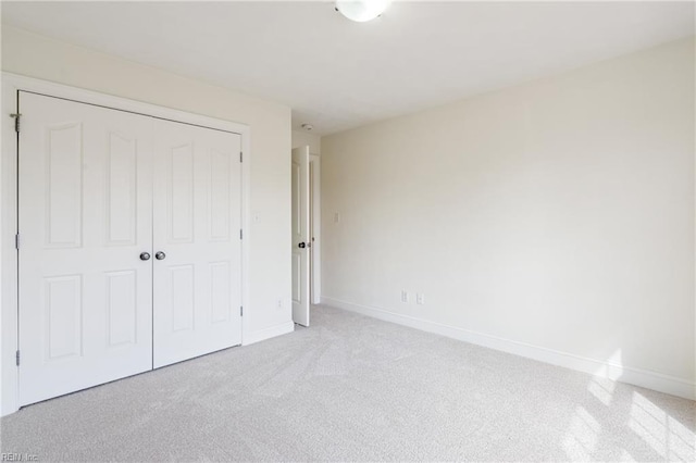 unfurnished bedroom featuring a closet, light colored carpet, and baseboards