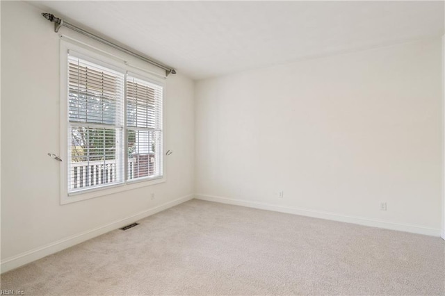 spare room featuring light carpet, visible vents, and baseboards