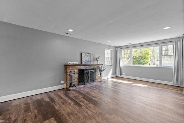 unfurnished living room with recessed lighting, visible vents, a brick fireplace, wood finished floors, and baseboards