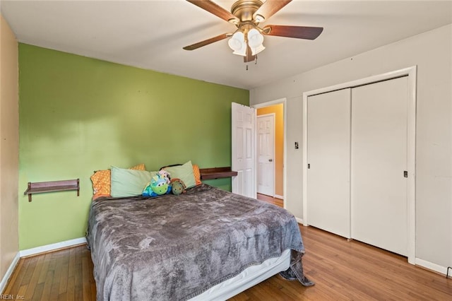 bedroom featuring ceiling fan, a closet, baseboards, and wood finished floors