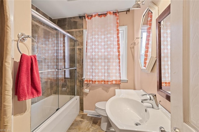 bathroom with enclosed tub / shower combo, a sink, toilet, and baseboards