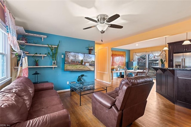 living room with ceiling fan, baseboards, and wood finished floors