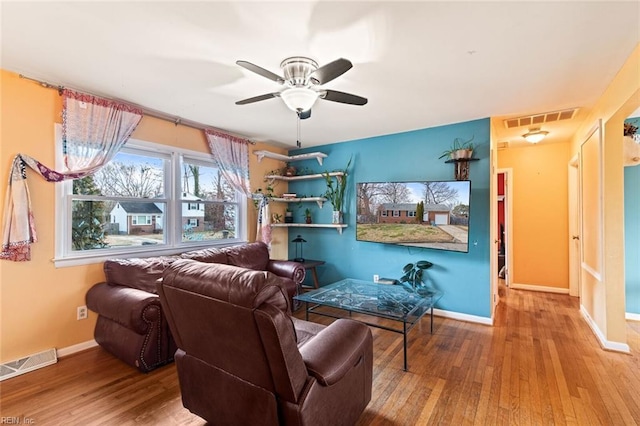 living area with visible vents, baseboards, and wood finished floors