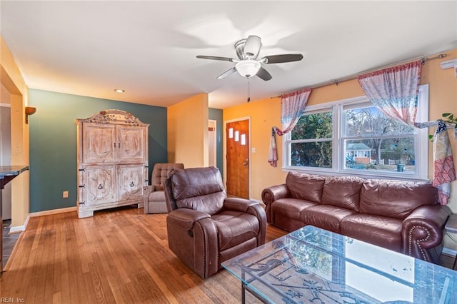 living area featuring light wood-style flooring, baseboards, and ceiling fan