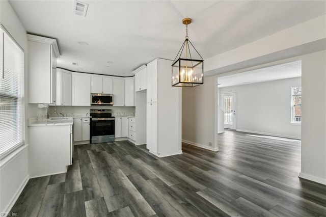 kitchen featuring light countertops, appliances with stainless steel finishes, dark wood-type flooring, and visible vents