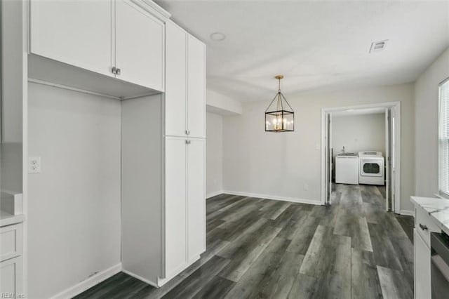 unfurnished dining area featuring dark wood-type flooring, visible vents, baseboards, and an inviting chandelier