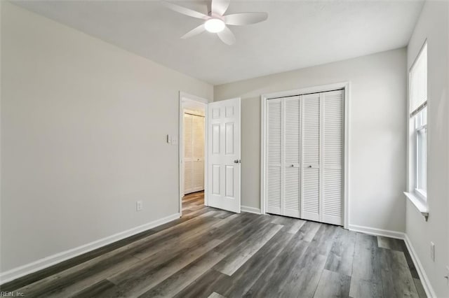 unfurnished bedroom featuring dark wood-style floors, ceiling fan, a closet, and baseboards