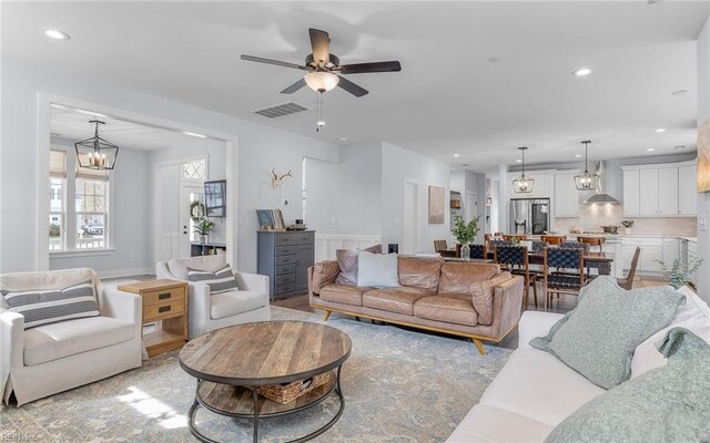 living area with recessed lighting, visible vents, and ceiling fan with notable chandelier