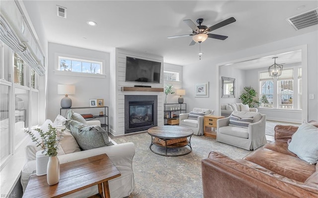 living area featuring visible vents, a large fireplace, and a healthy amount of sunlight