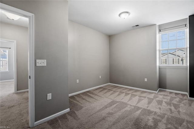 carpeted spare room featuring baseboards and visible vents