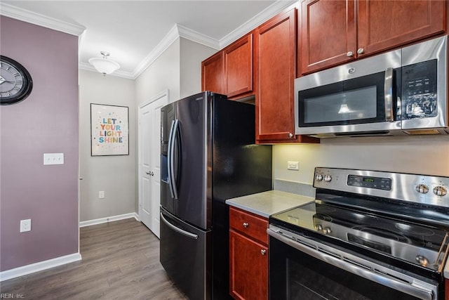 kitchen with baseboards, appliances with stainless steel finishes, ornamental molding, wood finished floors, and light countertops