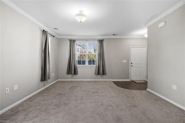 spare room with carpet, visible vents, crown molding, and baseboards