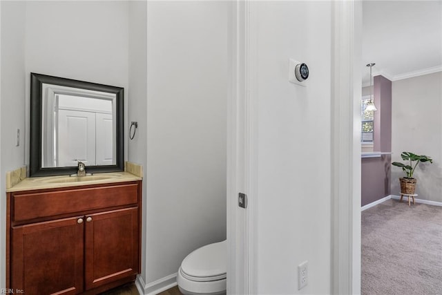 bathroom with toilet, crown molding, vanity, and baseboards