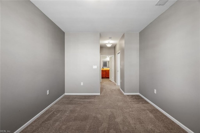 unfurnished room with carpet floors, visible vents, and baseboards