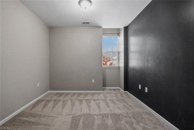 empty room featuring carpet, visible vents, and baseboards