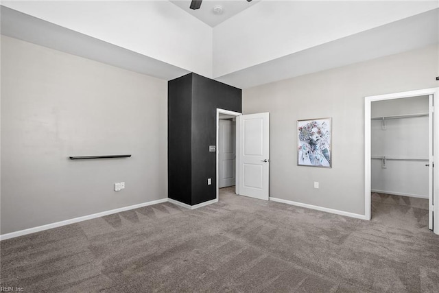 unfurnished bedroom featuring carpet floors, a ceiling fan, baseboards, a closet, and a walk in closet