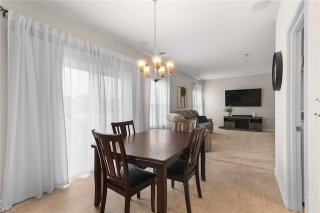 dining area with light colored carpet, visible vents, and an inviting chandelier