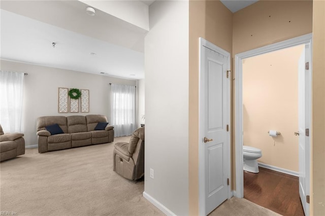 carpeted living area featuring baseboards