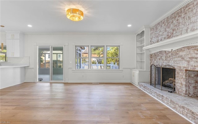 unfurnished living room featuring light wood finished floors, a fireplace, built in shelves, and crown molding