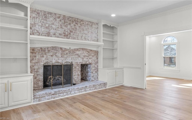 unfurnished living room featuring built in shelves, light wood-style flooring, a fireplace, baseboards, and crown molding