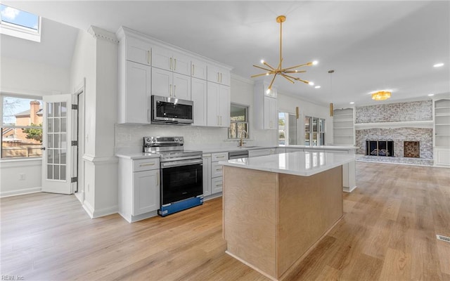 kitchen featuring a brick fireplace, plenty of natural light, stainless steel appliances, and light countertops