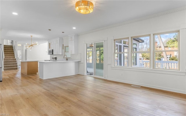 kitchen featuring decorative backsplash, light wood-style flooring, stainless steel microwave, a peninsula, and light countertops