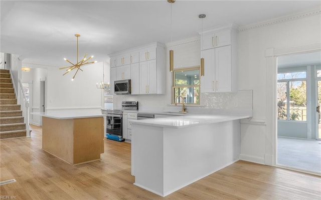 kitchen featuring a chandelier, a kitchen island, a sink, light countertops, and appliances with stainless steel finishes