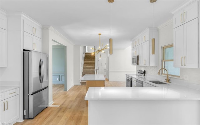 kitchen with light countertops, appliances with stainless steel finishes, a sink, and white cabinetry