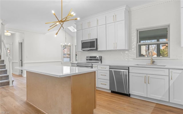 kitchen featuring stainless steel appliances, a chandelier, light countertops, and a sink