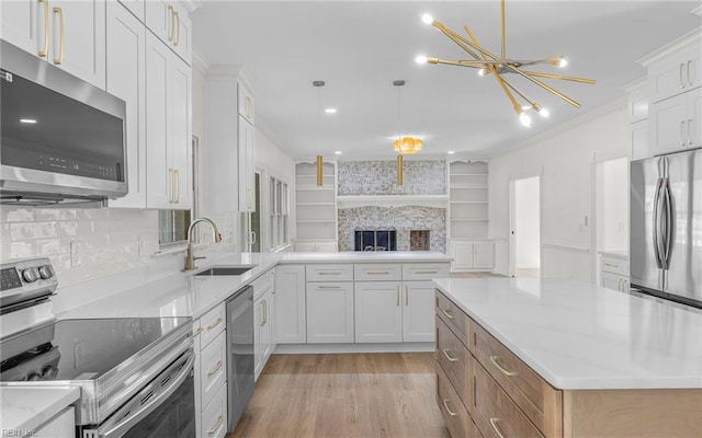 kitchen with ornamental molding, a peninsula, stainless steel appliances, light wood-type flooring, and a sink