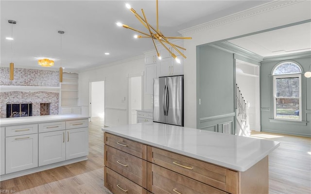 kitchen with light wood-style floors, open floor plan, ornamental molding, a brick fireplace, and freestanding refrigerator