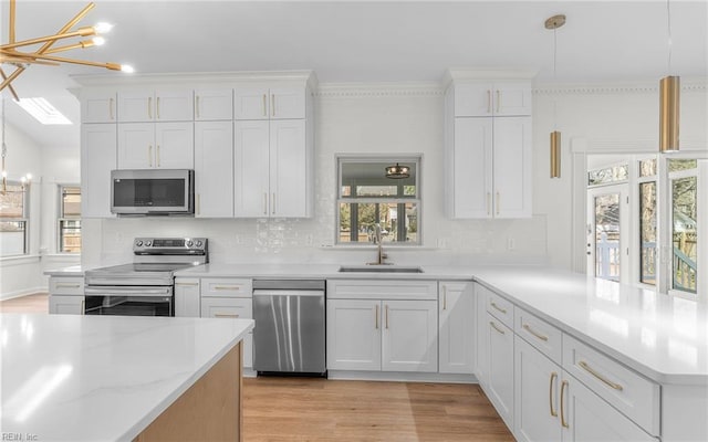 kitchen featuring appliances with stainless steel finishes, light wood-type flooring, white cabinets, and a sink