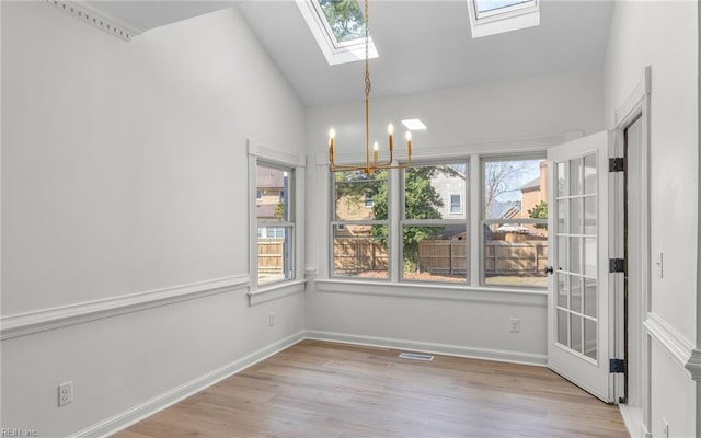 unfurnished dining area featuring lofted ceiling with skylight, visible vents, an inviting chandelier, and wood finished floors